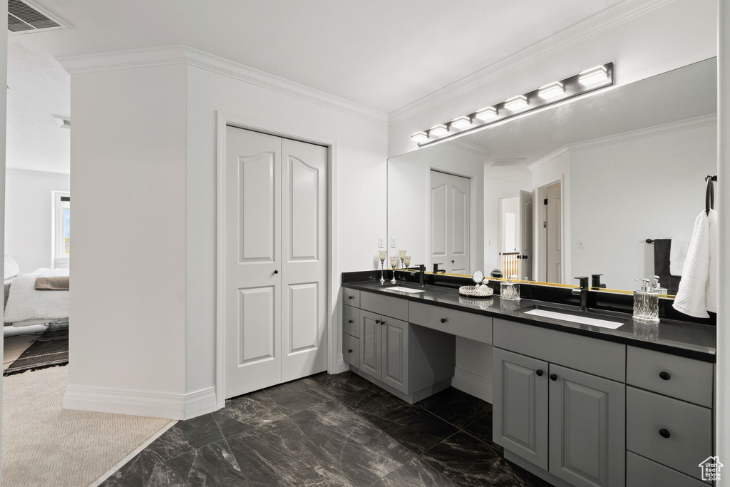 Full bathroom featuring marble finish floors, double vanity, ornamental molding, and baseboards