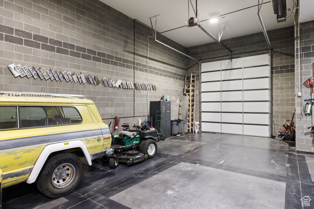 Garage featuring concrete block wall and a garage door opener
