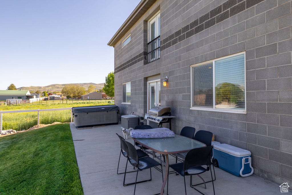 View of patio with a hot tub, grilling area, outdoor dining area, and a mountain view