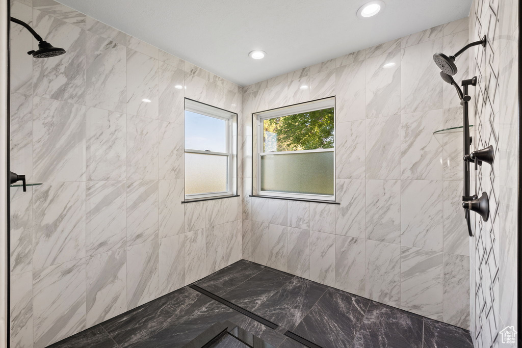Bathroom with tiled shower, marble finish floors, and recessed lighting