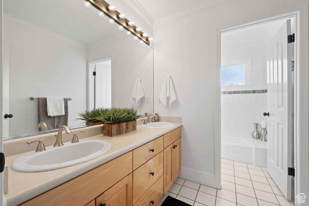 Bathroom featuring tile patterned floors, double vanity, crown molding, and baseboards