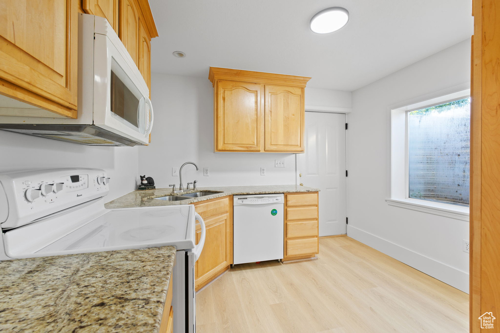 Kitchen featuring white appliances, a sink, light wood-type flooring, light brown cabinets, and light stone counters