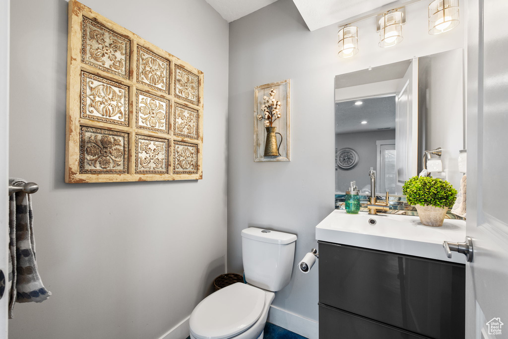 Bathroom with toilet, vanity, and baseboards