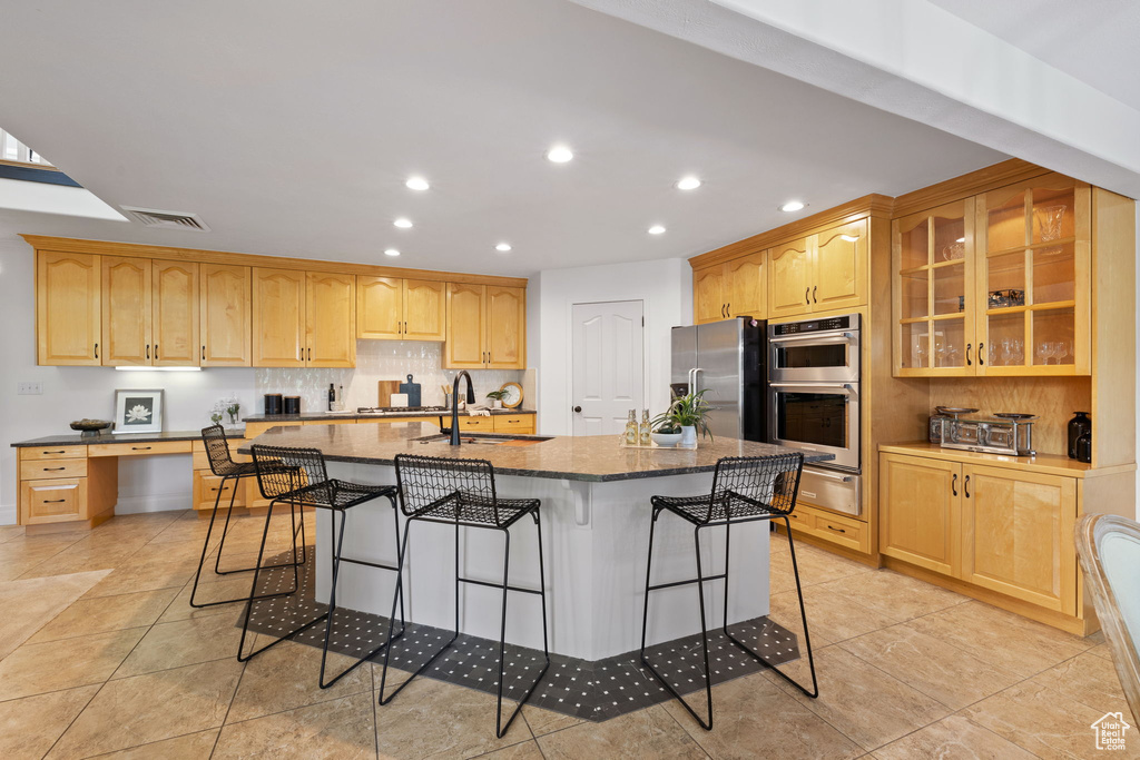 Kitchen featuring stainless steel appliances, a warming drawer, recessed lighting, a kitchen bar, and dark stone countertops