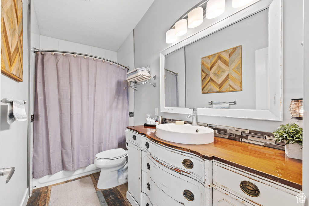 Full bathroom with toilet, vanity, and shower / bath combo with shower curtain