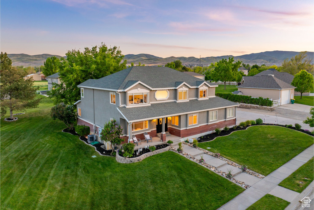 Traditional home with a garage, a yard, driveway, and a mountain view