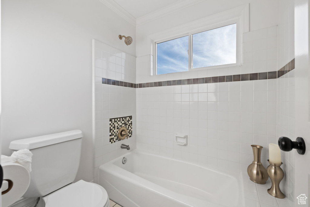 Full bathroom with toilet, ornamental molding, and bathing tub / shower combination