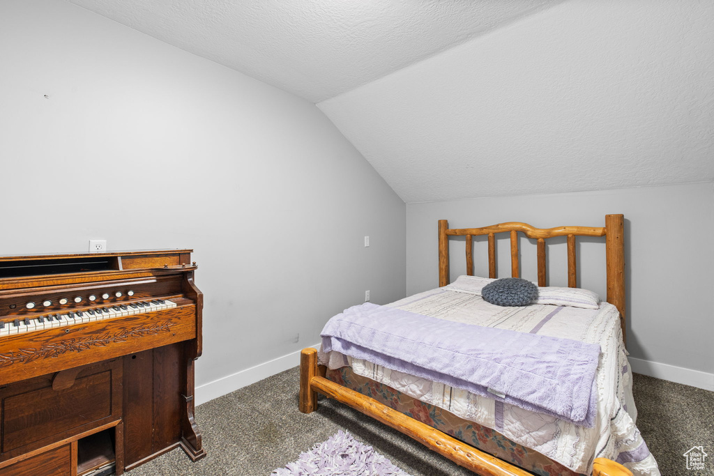 Bedroom featuring vaulted ceiling, carpet floors, baseboards, and a textured ceiling