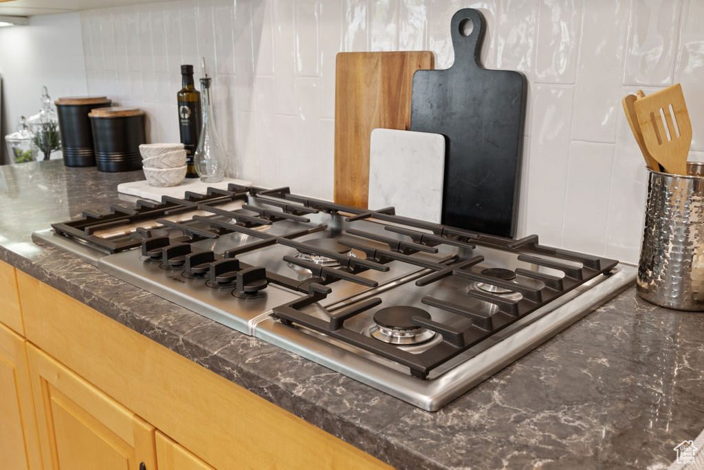 Kitchen view of stainless steel gas stovetop and dark countertops