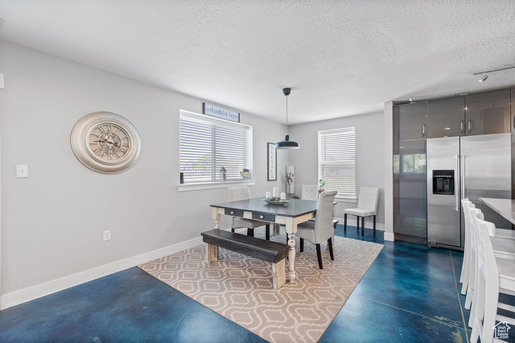 Dining room with concrete floors, baseboards, and a textured ceiling