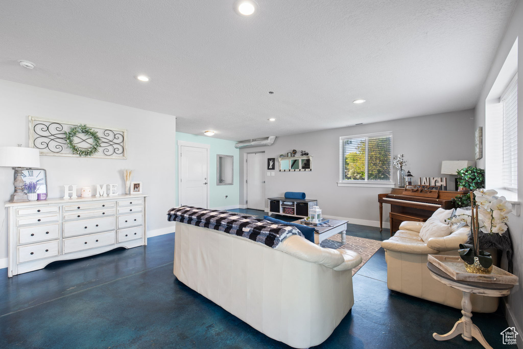 Living room with finished concrete flooring, baseboards, recessed lighting, and a wall mounted AC