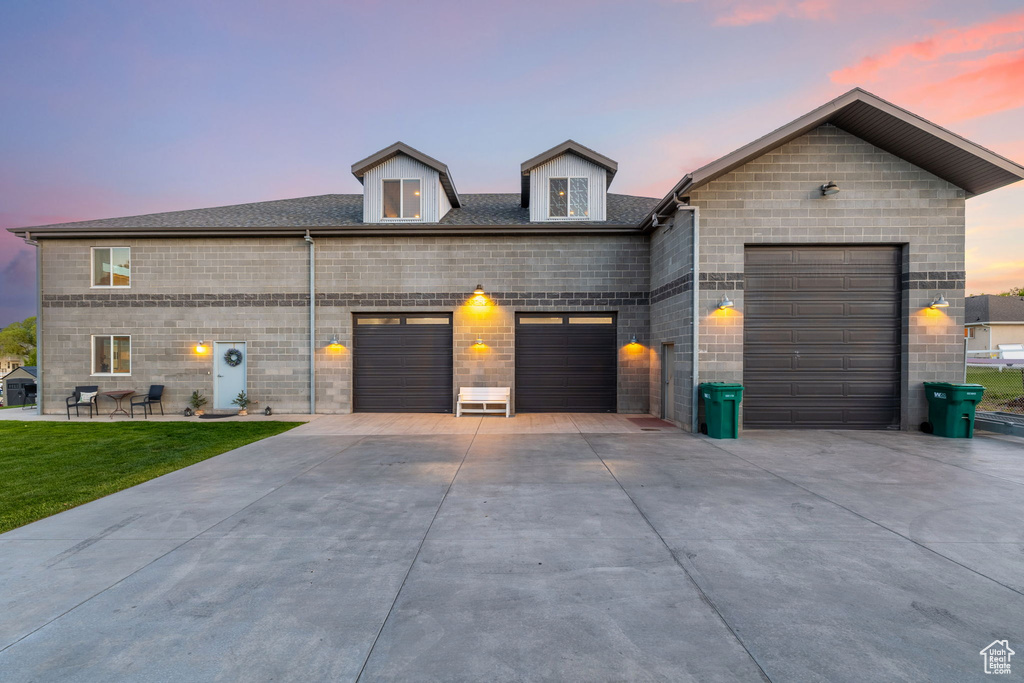 View of front of house featuring a garage, concrete driveway, and a lawn