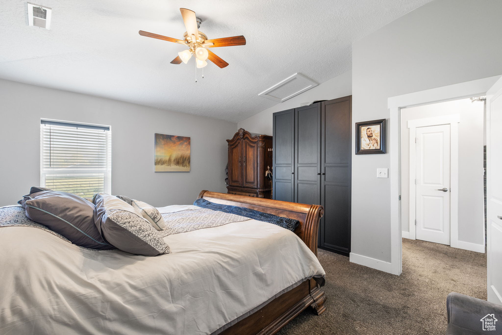 Bedroom featuring attic access, vaulted ceiling, dark carpet, a closet, and a ceiling fan