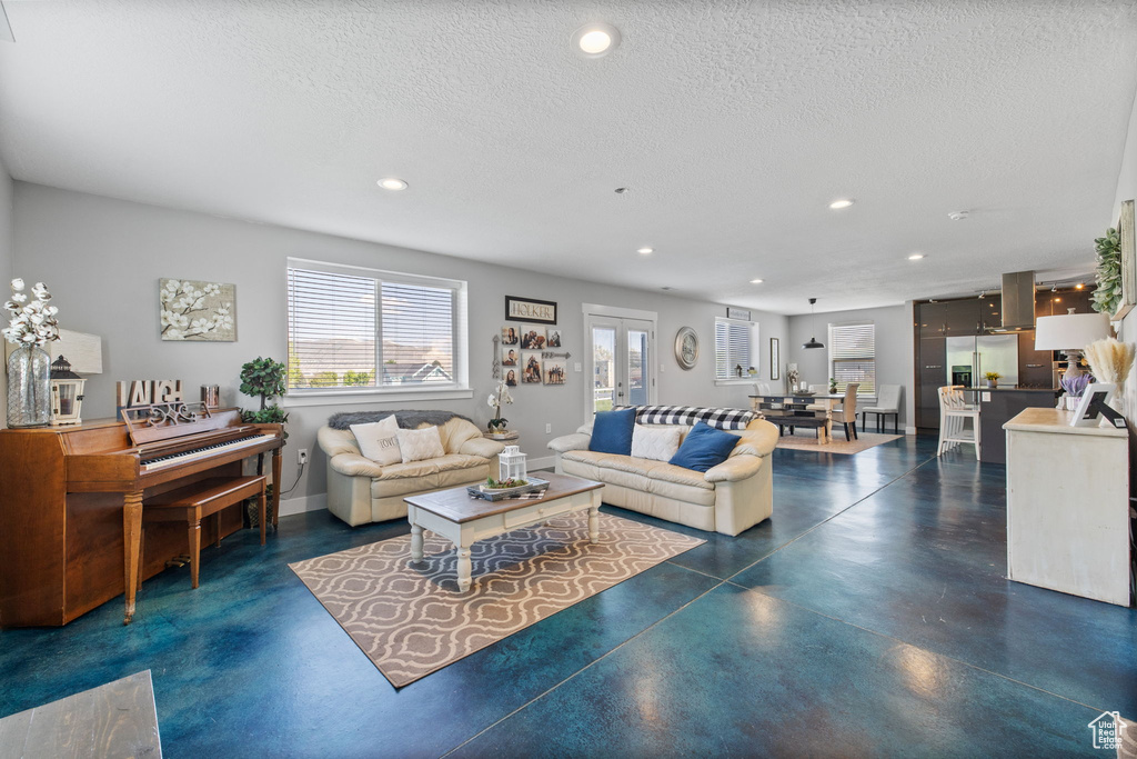Living area with finished concrete flooring, recessed lighting, a textured ceiling, and baseboards