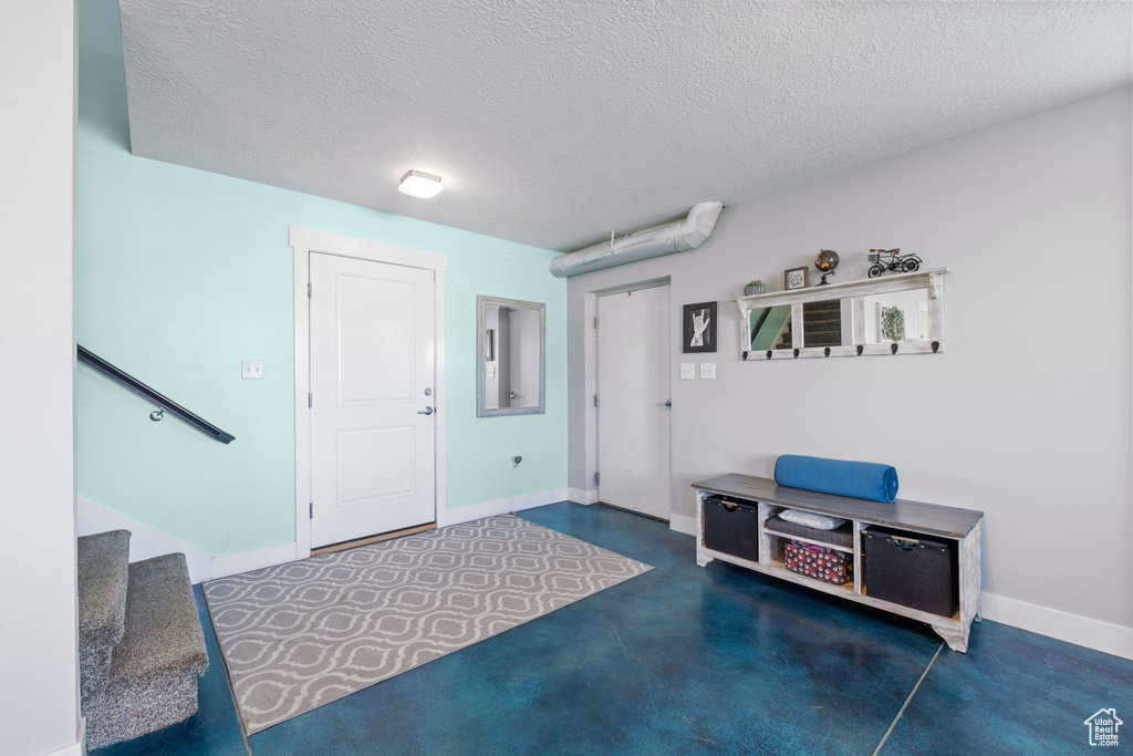 Entrance foyer with stairway, a textured ceiling, and baseboards