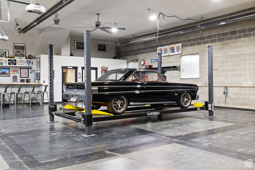 Garage with concrete block wall, ceiling fan, and a garage door opener