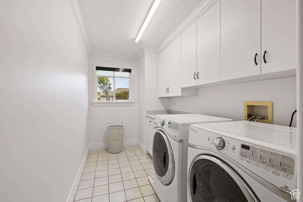 Laundry area with cabinet space, crown molding, washer and dryer, baseboards, and light tile patterned flooring