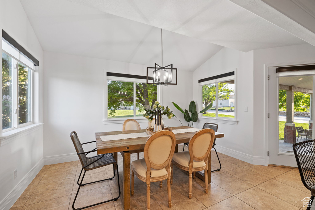 Dining space with lofted ceiling, baseboards, a chandelier, and light tile patterned flooring