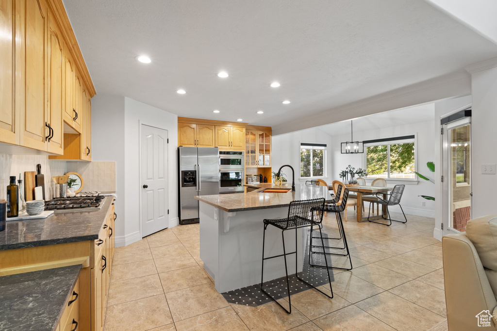 Kitchen featuring appliances with stainless steel finishes, a sink, a kitchen breakfast bar, baseboards, and recessed lighting