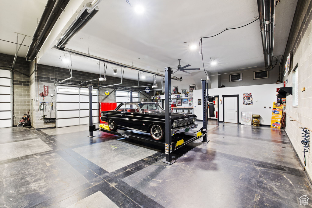 Garage with concrete block wall, a garage door opener, and a ceiling fan