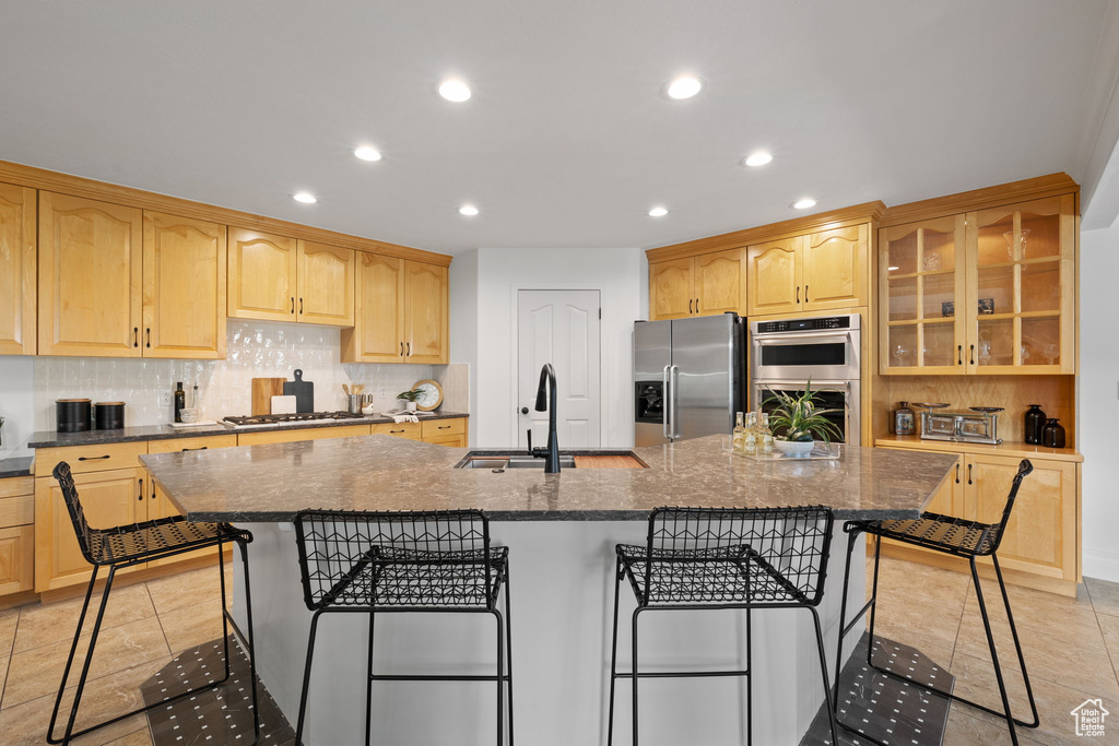 Kitchen with stainless steel appliances, recessed lighting, a kitchen bar, a sink, and backsplash