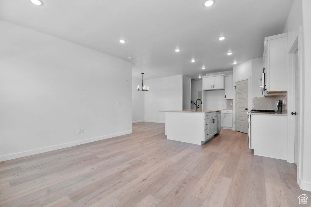 Kitchen with a chandelier, open floor plan, a center island with sink, light wood-style flooring, and recessed lighting