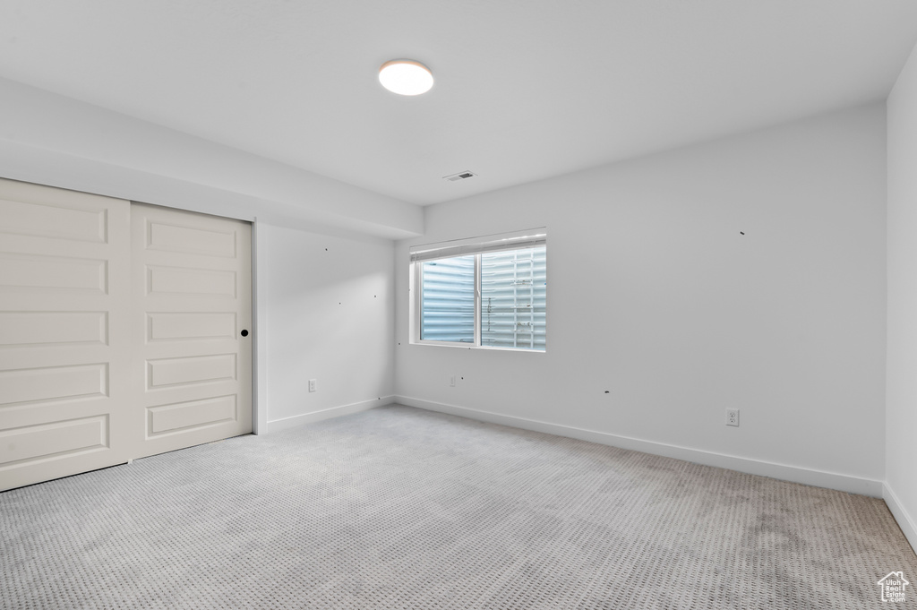 Unfurnished bedroom with light colored carpet, baseboards, and a closet