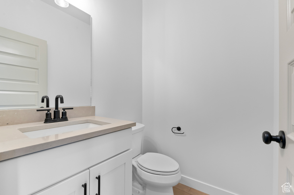 Bathroom featuring vanity, toilet, and baseboards