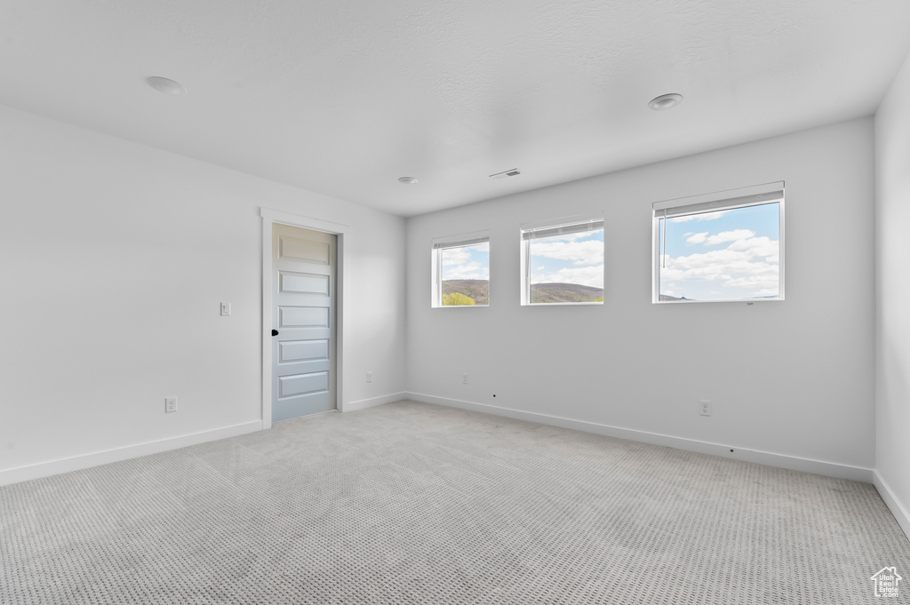 Spare room featuring light colored carpet and baseboards
