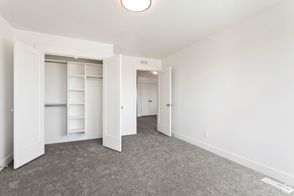 Unfurnished bedroom featuring carpet, a closet, and baseboards
