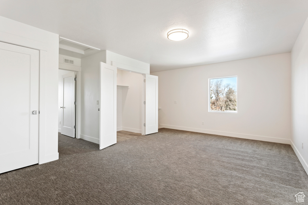 Unfurnished bedroom featuring dark carpet and baseboards