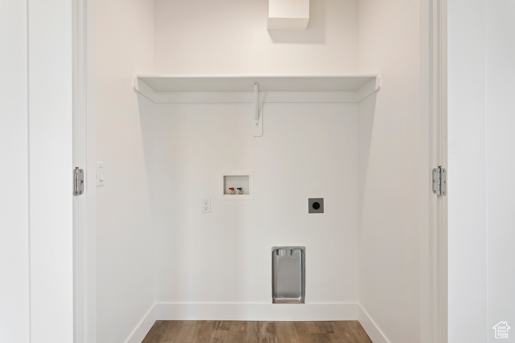 Laundry area with hookup for a washing machine, hookup for an electric dryer, wood finished floors, and baseboards
