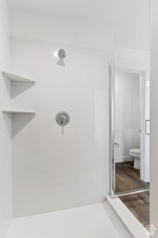 Bathroom with toilet, wood finished floors, and a shower