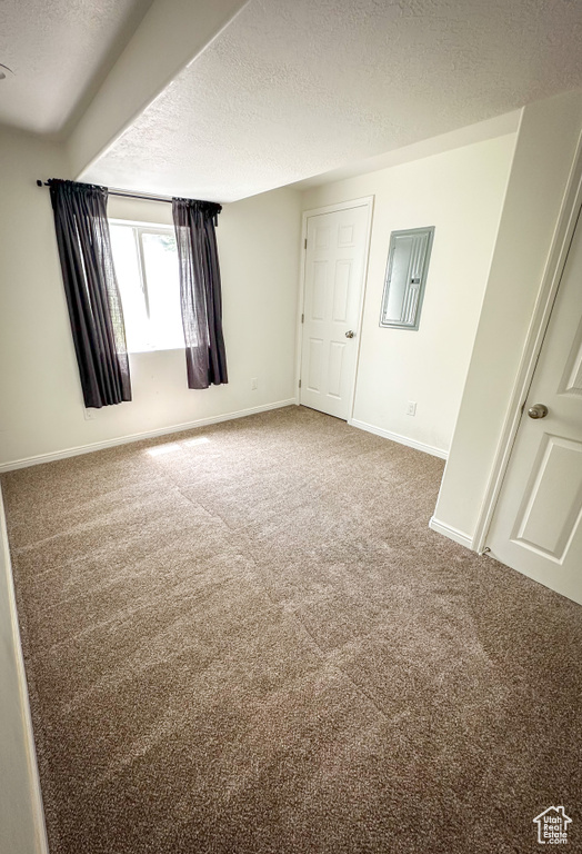 Carpeted spare room with a textured ceiling and baseboards