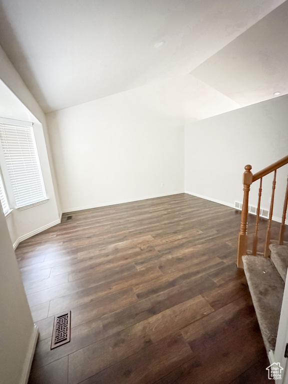 Additional living space with lofted ceiling, dark wood-type flooring, stairway, and baseboards