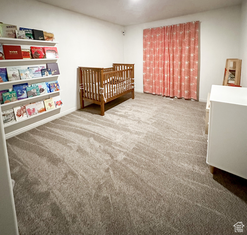 Bedroom with carpet floors, a crib, and baseboards