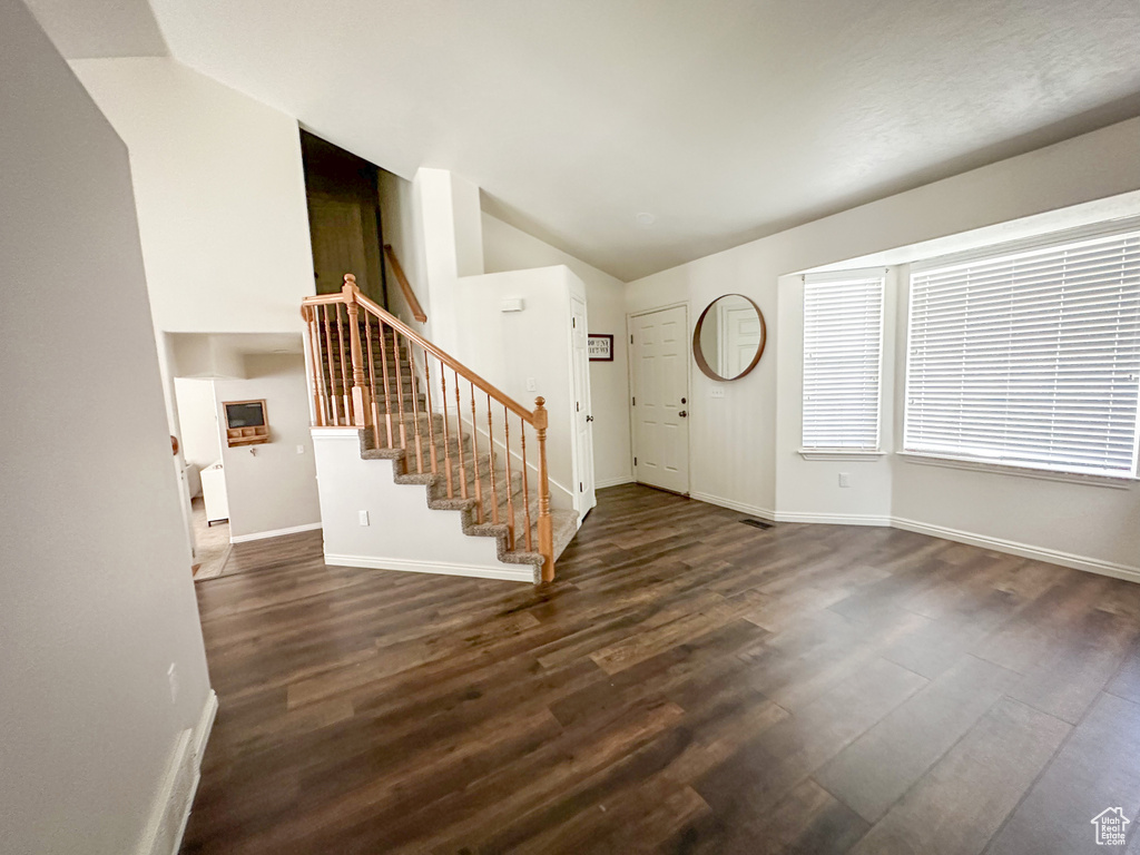 Foyer with vaulted ceiling, wood finished floors, stairway, and baseboards