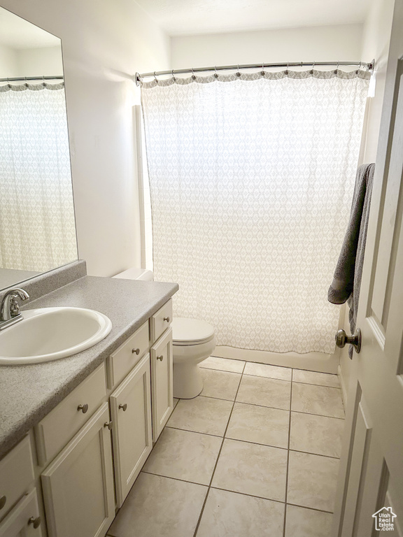 Bathroom featuring tile patterned flooring, toilet, vanity, and a shower with shower curtain
