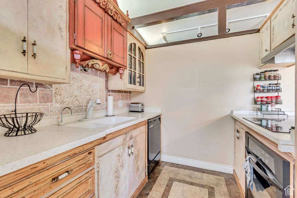 Kitchen featuring black appliances, a sink, baseboards, tasteful backsplash, and inlaid floor details