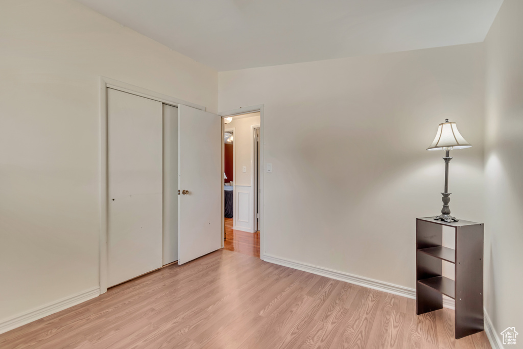 Unfurnished bedroom featuring light wood-type flooring, a closet, and baseboards