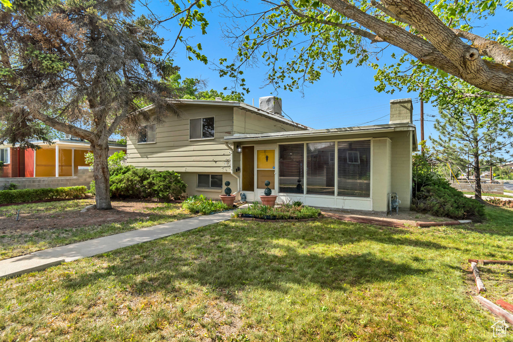 Split level home featuring a chimney and a front yard
