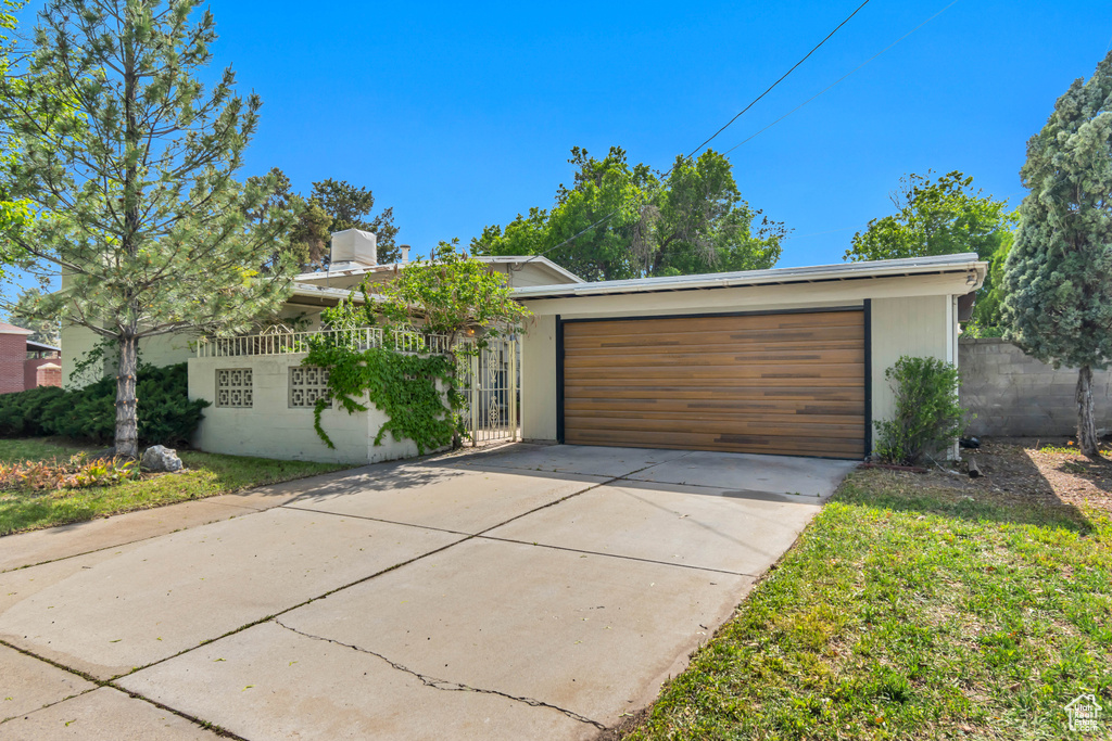 View of front of home with fence, an attached garage, and driveway