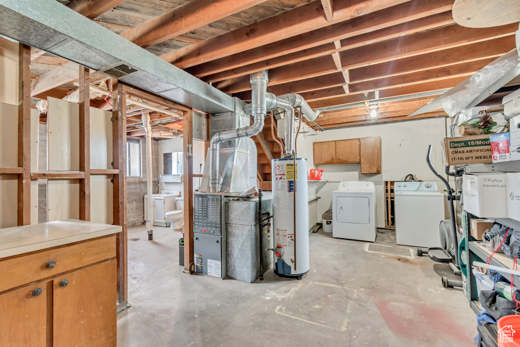 Unfinished basement featuring gas water heater, washer and clothes dryer, and heating unit