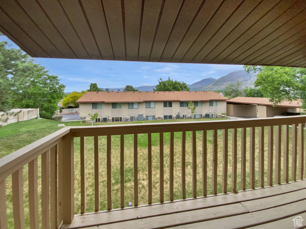 Wooden deck with a residential view, a mountain view, and a lawn