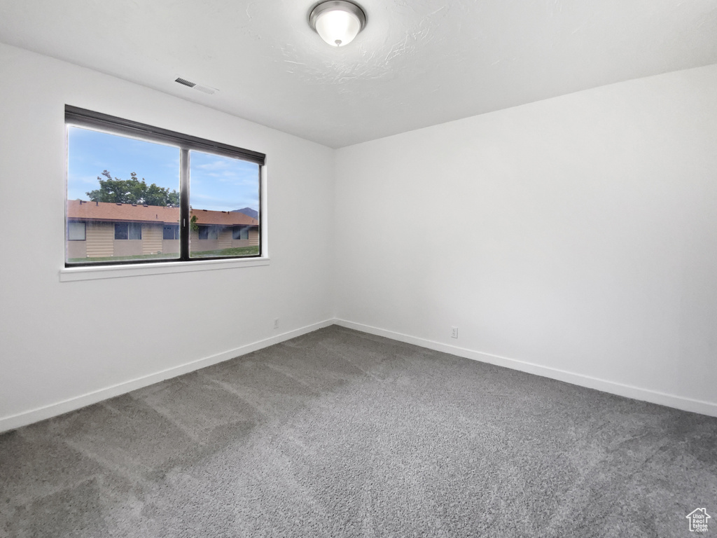 Spare room featuring dark colored carpet and baseboards