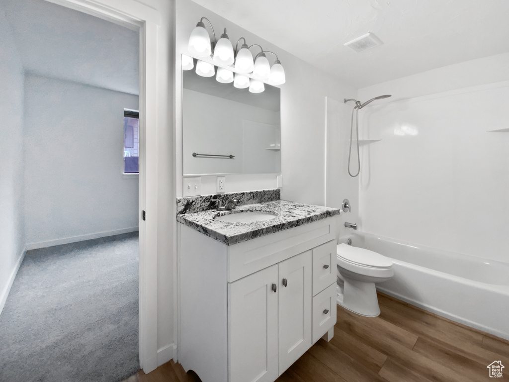 Full bath with  shower combination, vanity, toilet, and wood finished floors