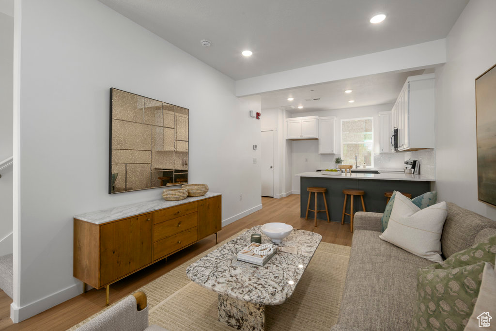 Living area with baseboards, light wood finished floors, and recessed lighting
