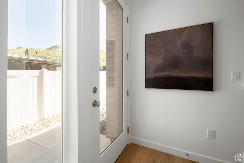 Doorway with wood finished floors and baseboards