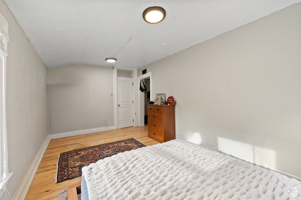 Bedroom featuring wood finished floors, baseboards, and lofted ceiling
