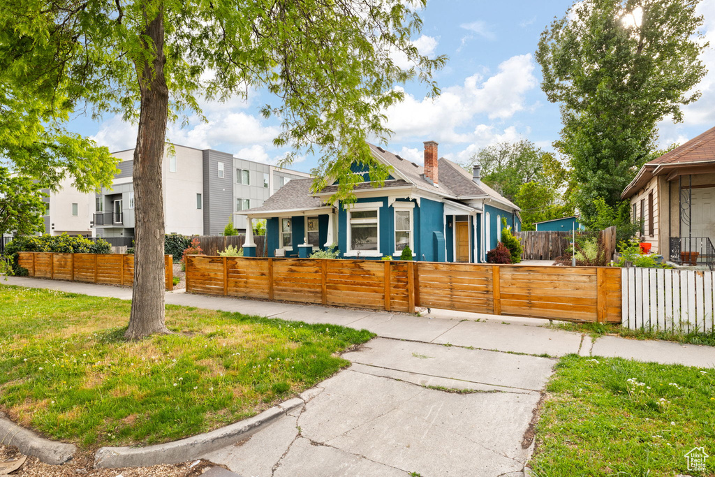 View of property exterior with roof with shingles, a fenced front yard, a gate, and a chimney